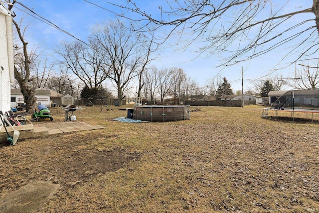 view of yard featuring an outbuilding, a storage shed, an outdoor pool, a trampoline, and a patio area