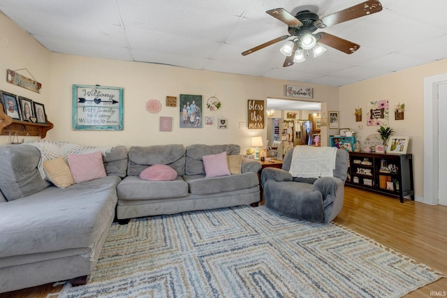 living area with a paneled ceiling, ceiling fan, and wood finished floors