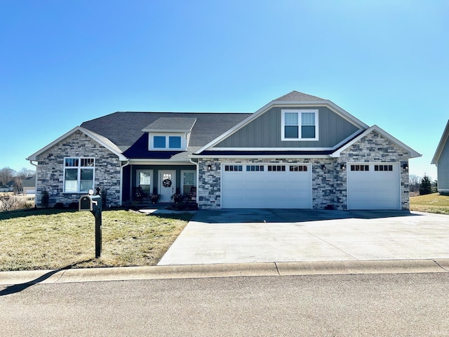 craftsman-style house featuring driveway, stone siding, and a front yard