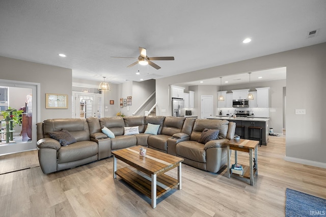 living area featuring stairs, light wood finished floors, visible vents, and recessed lighting