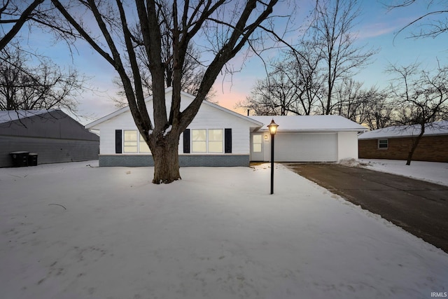 ranch-style home featuring driveway, brick siding, and an attached garage