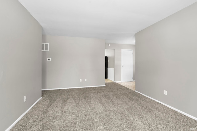 unfurnished room with baseboards, visible vents, and light colored carpet