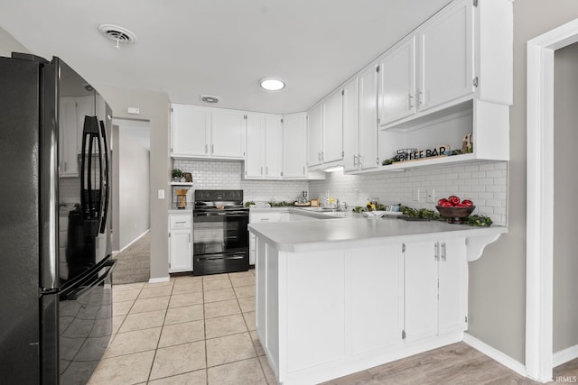 kitchen featuring tasteful backsplash, light countertops, visible vents, a peninsula, and black appliances