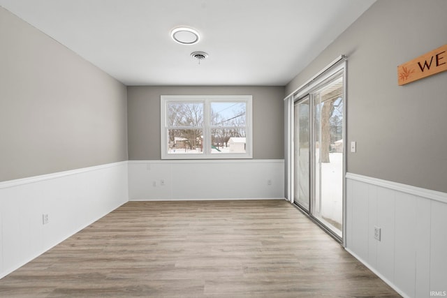 spare room with visible vents, wood finished floors, and wainscoting