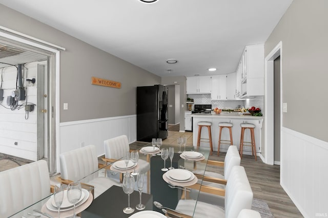 dining area featuring a wainscoted wall and light wood-style flooring