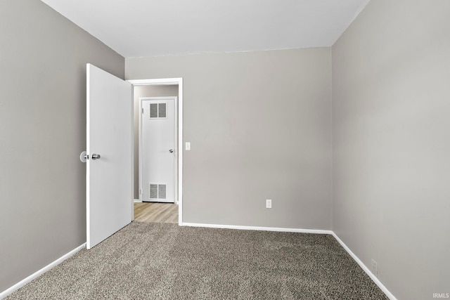 carpeted spare room with visible vents and baseboards