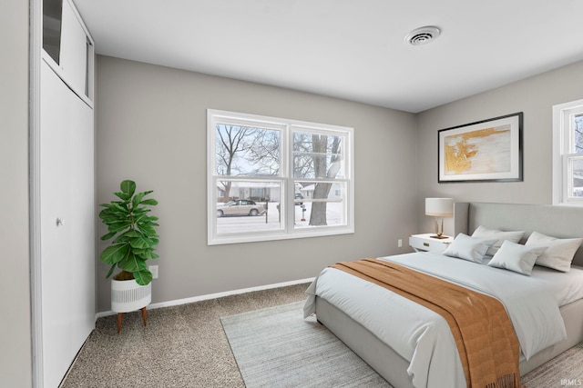 bedroom featuring visible vents, light carpet, and baseboards