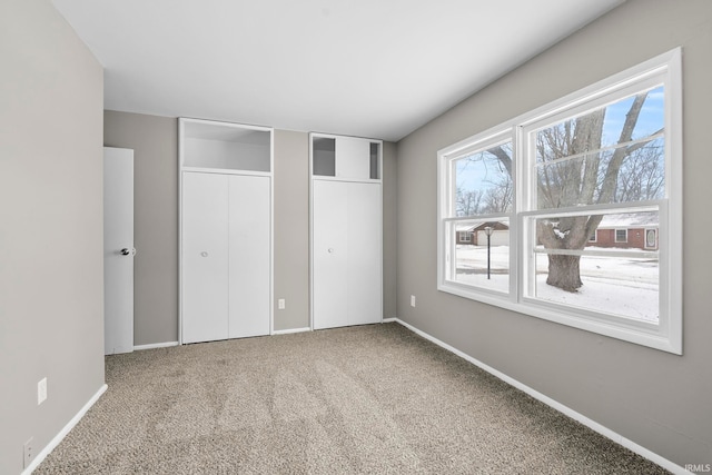 unfurnished bedroom featuring carpet floors, baseboards, and multiple closets