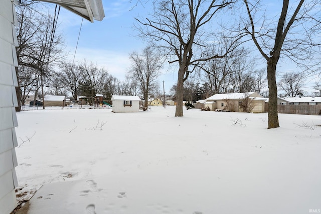 yard covered in snow featuring a shed and an outdoor structure