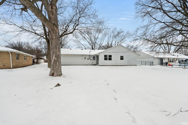 snow covered property with fence and an attached garage