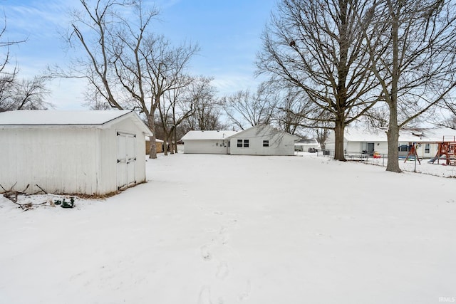 yard layered in snow featuring a garage and an outdoor structure