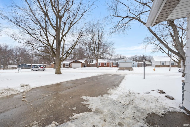 yard covered in snow featuring a detached garage and a residential view