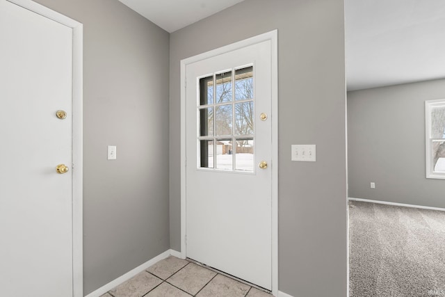 doorway with light carpet, baseboards, and light tile patterned floors