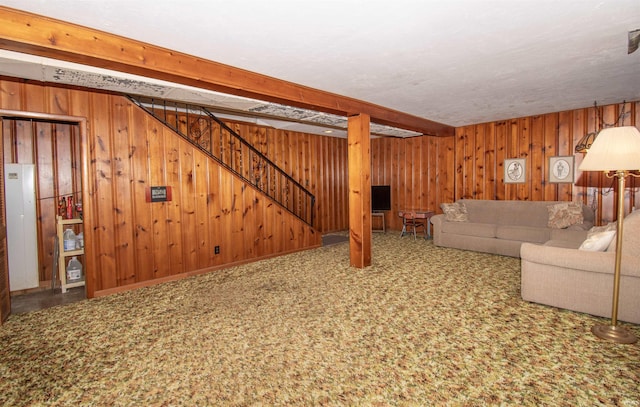 unfurnished living room featuring beamed ceiling, wooden walls, and stairs