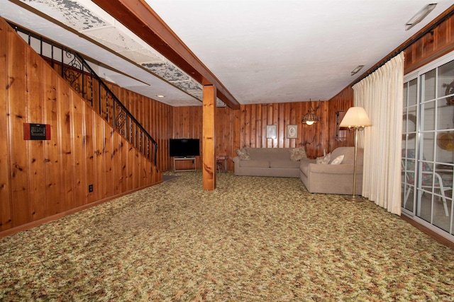 unfurnished living room featuring stairway, carpet, and wooden walls