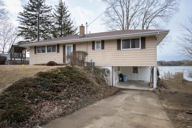 view of front facade with a carport, concrete driveway, a chimney, and central AC unit