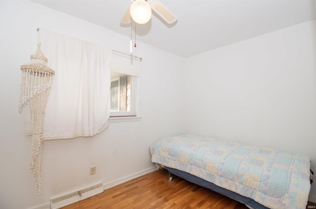 bedroom with a ceiling fan, baseboards, baseboard heating, and wood finished floors