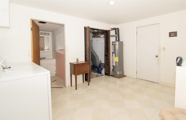 interior space with light floors, washing machine and clothes dryer, water heater, a sink, and laundry area