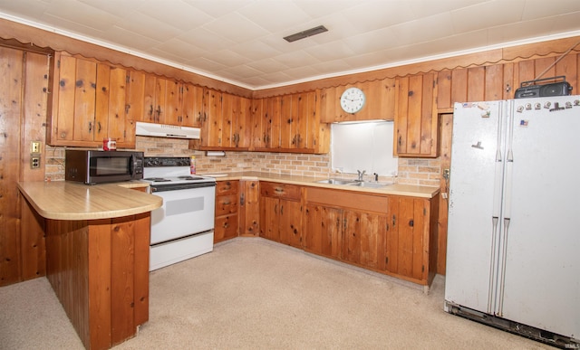 kitchen featuring white appliances, brown cabinetry, light countertops, under cabinet range hood, and a sink