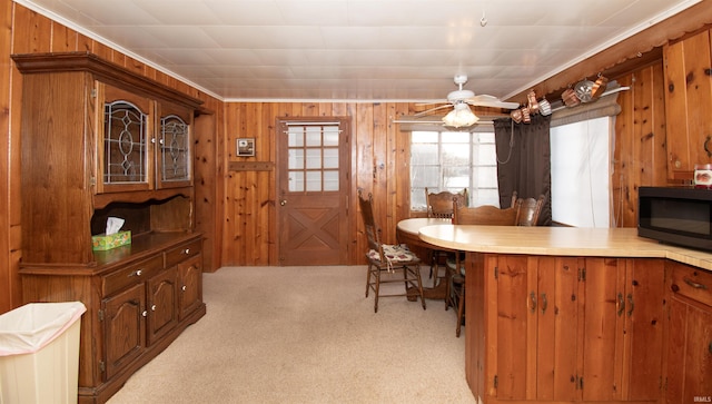 kitchen with black microwave, light carpet, and wooden walls