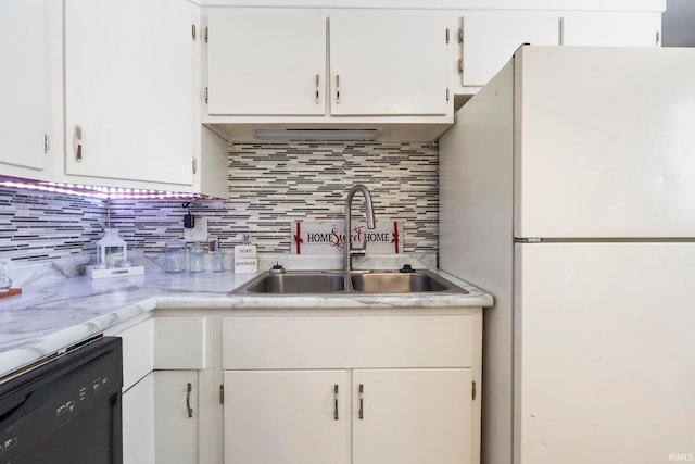 kitchen featuring dishwasher, a sink, freestanding refrigerator, and white cabinetry