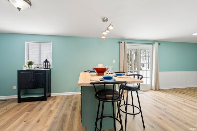 dining room featuring baseboards, a wainscoted wall, and light wood finished floors