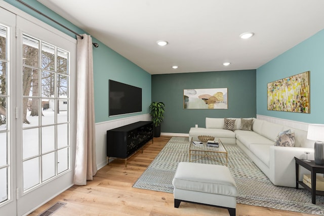 living room featuring wainscoting, light wood-style flooring, visible vents, and recessed lighting