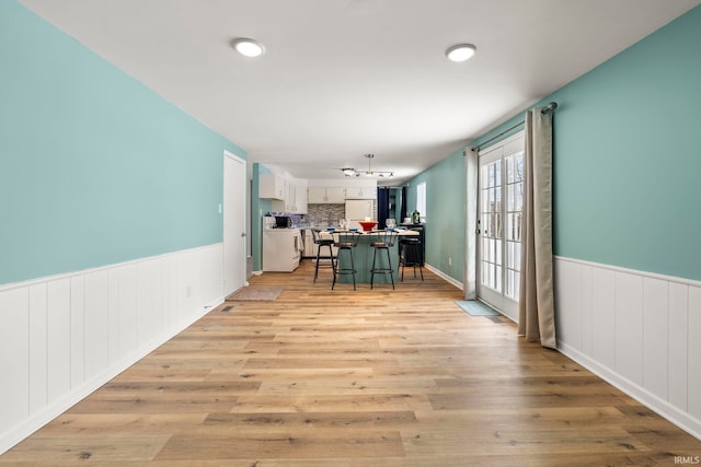 dining area with light wood-type flooring and wainscoting