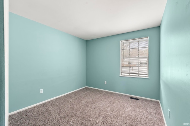 empty room featuring carpet, visible vents, and baseboards