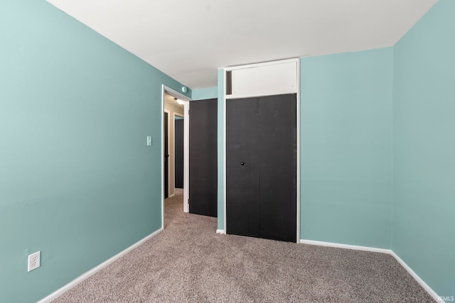 unfurnished bedroom featuring a closet, baseboards, and carpet flooring