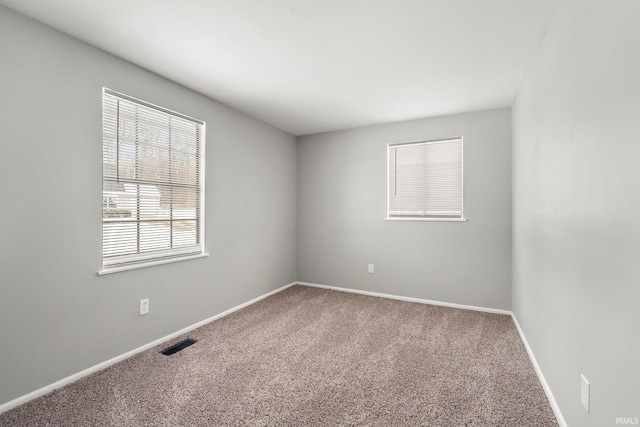 carpeted spare room with visible vents and baseboards