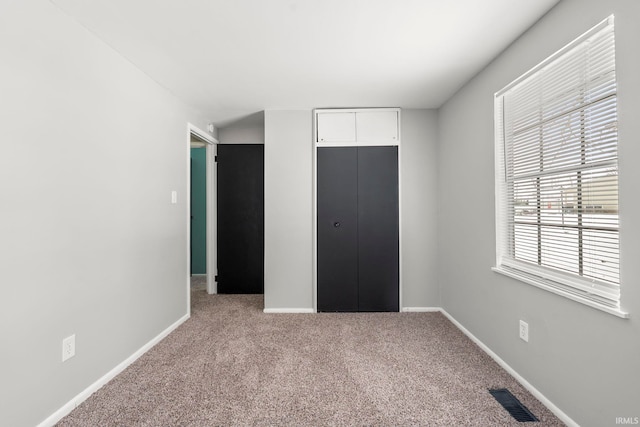 unfurnished bedroom featuring baseboards, a closet, visible vents, and carpet flooring