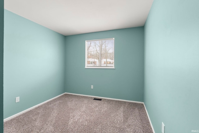 spare room with carpet floors, visible vents, and baseboards