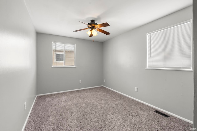 empty room with carpet, visible vents, baseboards, and ceiling fan