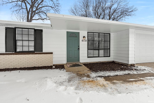 view of exterior entry with a garage and brick siding