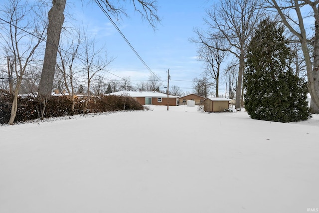 yard layered in snow with a storage shed and an outdoor structure