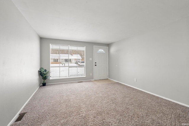 spare room featuring light colored carpet, visible vents, and baseboards