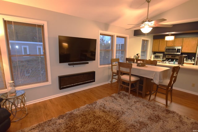 dining area featuring a ceiling fan, vaulted ceiling, baseboards, and wood finished floors