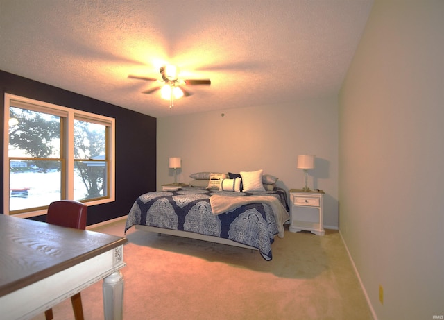 carpeted bedroom with ceiling fan, a textured ceiling, and baseboards