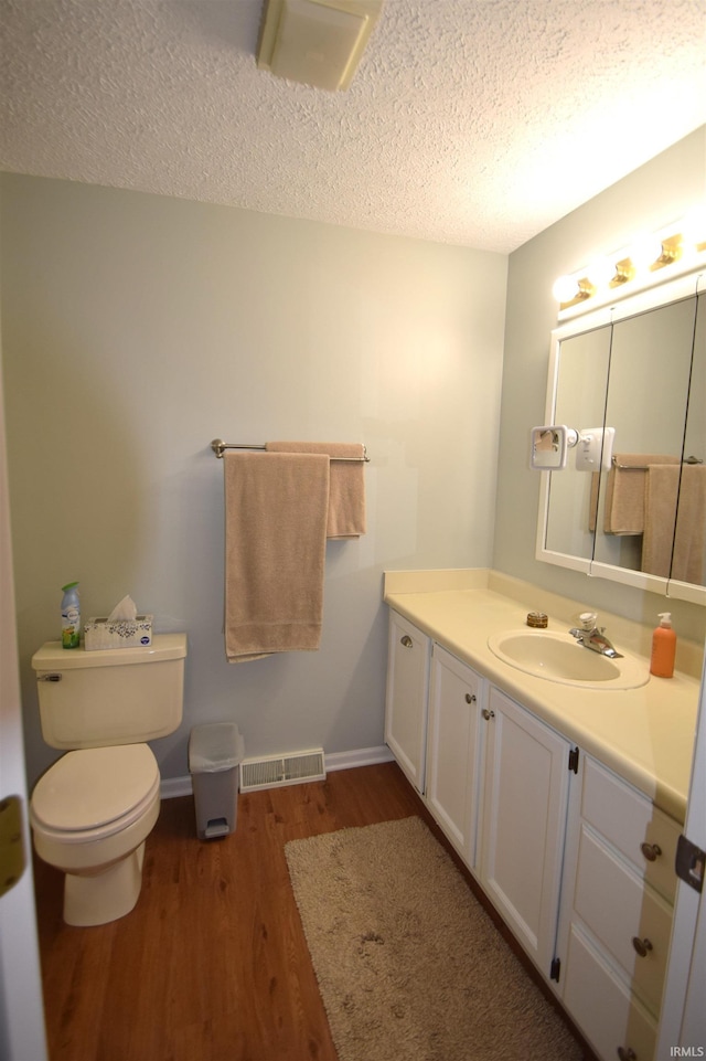 bathroom with a textured ceiling, visible vents, wood finished floors, and vanity