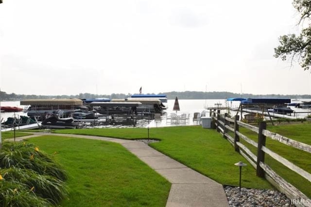 view of dock with a water view, a yard, and fence