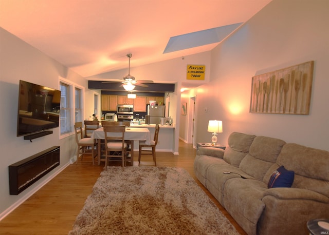 living room with lofted ceiling, ceiling fan, wood finished floors, and baseboards