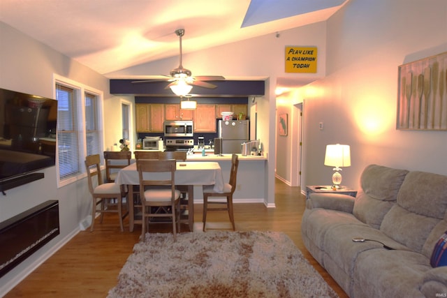 living area featuring lofted ceiling, wood finished floors, and baseboards