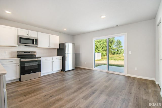 kitchen featuring white cabinets, appliances with stainless steel finishes, light countertops, light wood-type flooring, and backsplash