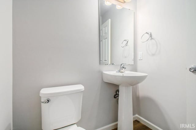 half bath featuring toilet, baseboards, and wood finished floors