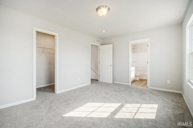 unfurnished bedroom featuring carpet, a spacious closet, baseboards, and visible vents