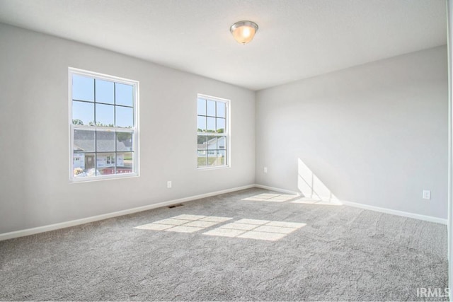 carpeted spare room with visible vents and baseboards