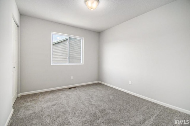 carpeted spare room featuring visible vents, a textured ceiling, and baseboards