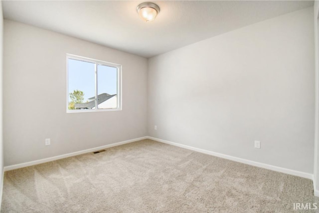 empty room featuring carpet floors, visible vents, and baseboards