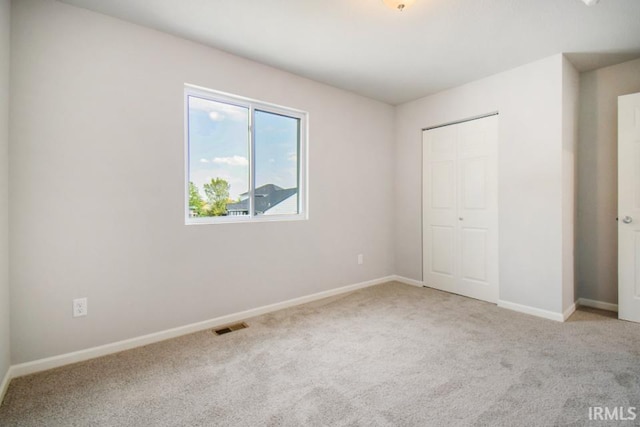 unfurnished bedroom featuring carpet floors, baseboards, visible vents, and a closet